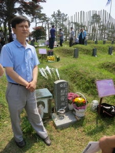 Lee Shin, activist, stands beside the grave of a man tortured to death for writing a book exposing the truth about the Gwangju uprising, a man from who he draws personal strength.